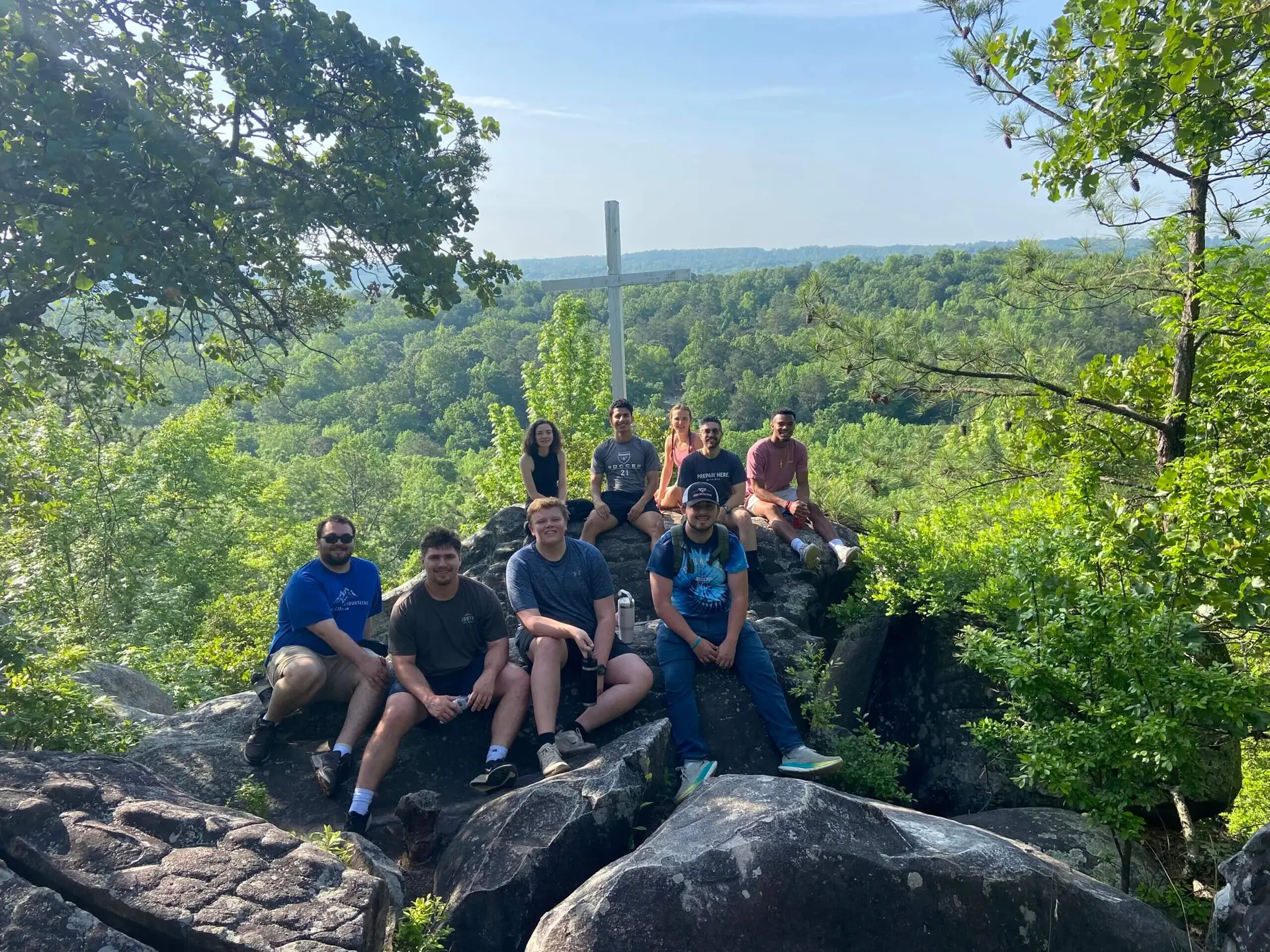 Auburn University Montgomery BCM leadership team students pose for picture on large rock overlooking wooded area