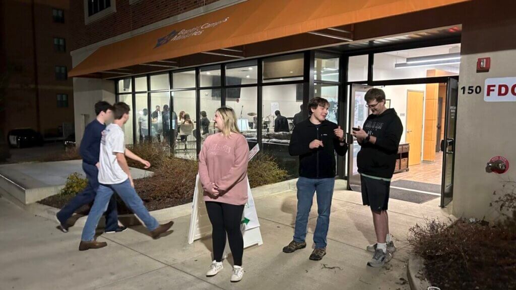 College students stand outside and walk in to Auburn University Baptist Campus Ministries building